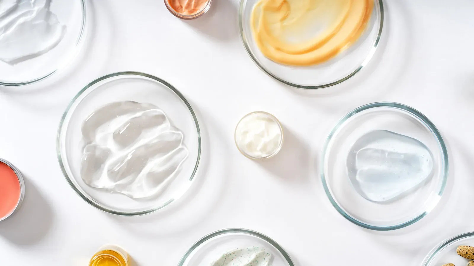 Muestras de cremas, geles y aceites sobre platos de vidrio.